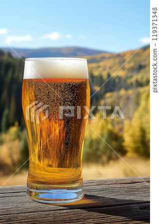 Glass of beer with a scenic mountain vista in the background, tranquil and inviting 119371348