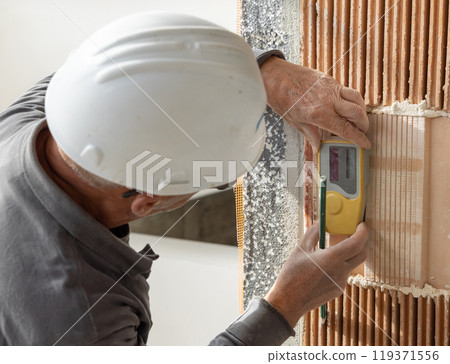 Craftsman measuring with horizontal rotary laser level. Construction or renovation site 119371556