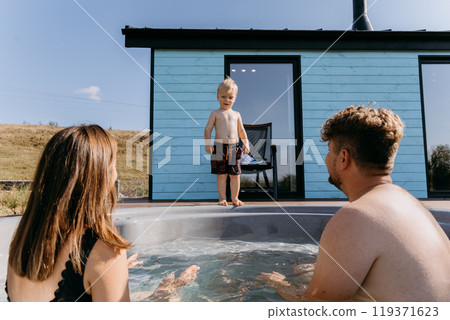 Toddler preparing to jump into a family hot tub on a sunny day, enjoying playful moments outdoors Toddler preparing to jump into a family hot tub on a sunny day, enjoying playful moments outdoors 119371623
