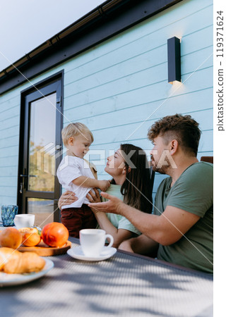 Loving family sharing joyful moments at an outdoor breakfast, creating memories together Loving family sharing joyful moments at an outdoor breakfast, creating memories together 119371624