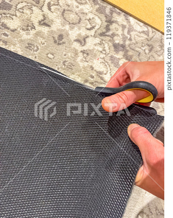 Closeup of hands holding scissors and cutting black rubber fabric . High quality photo 119371846