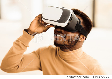 VR Technology. Black man wearing virtual reality glasses experiencing innovative technology, copy space VR Technology. Black man wearing virtual reality glasses experiencing innovative technology, copy space 119372777
