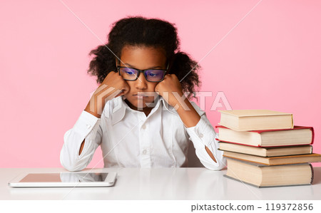 Sad African Schoolgirl Sitting At Digital Tablet And Books, Bored And Tired Of School Learning Over Yellow Studio Background Sad African Schoolgirl Sitting At Digital Tablet And Books, Bored And Tired Of School Learning Over Yellow Studio Background 119372856