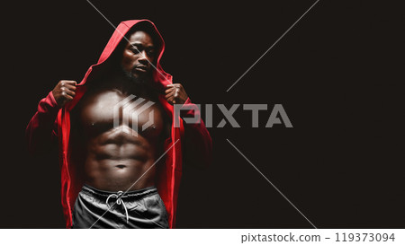A muscular man in a red hoodie removes his jacket to reveal his toned physique during a workout. 119373094