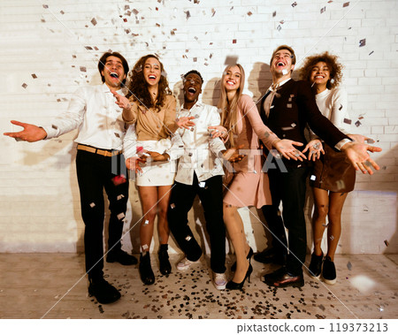 Party Mood. Excited Millennials Students Standing Showered With Confetti Having Fun Celebrating Event Against White Wall Indoor Party Mood. Excited Millennials Students Standing Showered With Confetti Having Fun Celebrating Event Against White Wall Indoor 119373213