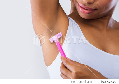 Cropped of black model shaving her armpit over grey background 119373230