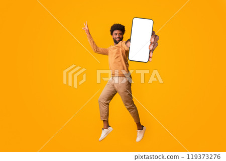 Everything is gonna be allright. Active african man gesturing peace while jumping in the air, orange background Everything is gonna be allright. Active african man gesturing peace while jumping in the air, orange background 119373276