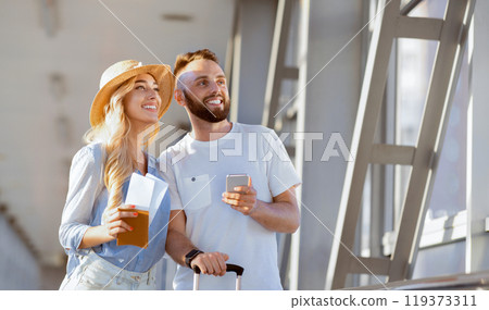 Traveling concept. Young couple in airport waiting for departure, looking aside Traveling concept. Young couple in airport waiting for departure, looking aside 119373311