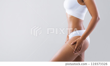 Beauty concept. Young afro woman showing her beautiful body over grey studio background with empty space, cropped 119373326