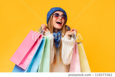 Winter big sale. Laughing young woman in blue hat and sunglasses with shopping bags, pink studio background 119373362