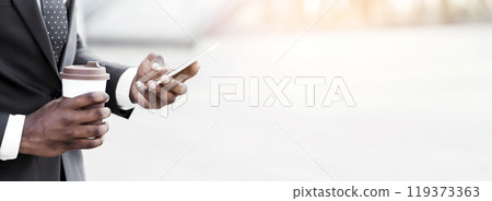 Always In Touch. Black Business Guy Using Phone Holding Coffee Cup Walking In Urban Area. Free Space, Closeup 119373363