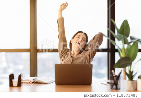 Little Break At Work. Smiling girl sitting in modern office, stretching arms above her head, empty space Little Break At Work. Smiling girl sitting in modern office, stretching arms above her head, empty space 119373493