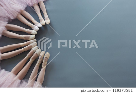 Ballet background. Little ballerinas legs in pointe shoes on floor, top view, copy space Ballet background. Little ballerinas legs in pointe shoes on floor, top view, copy space 119373591