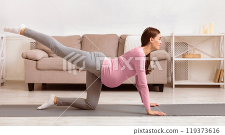 Prenatal Exercises For Healthy Delivery. Pregnant woman doing back leg raises or donkey kick on yoga mat. Copy space Prenatal Exercises For Healthy Delivery. Pregnant woman doing back leg raises or donkey kick on yoga mat. Copy space 119373616