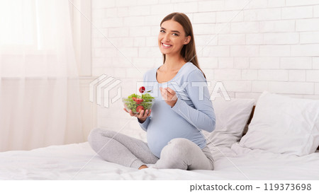 Pregnancy Healthy Diet. Pregnant Girl Holding Vegetable Salad In Bowl Smiling To Camera Sitting In Bed At Home. Empty Space Pregnancy Healthy Diet. Pregnant Girl Holding Vegetable Salad In Bowl Smiling To Camera Sitting In Bed At Home. Empty Space 119373698