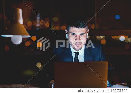Concentrated Business Guy At Laptop Working Wearing Earbuds Overnight Sitting Alone In Modern Office. Copy Space, Selective Focus 119373721