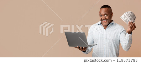 Cashback and online shopping concept. Excited mature african american man holding lots of money and laptop, orange background 119373783