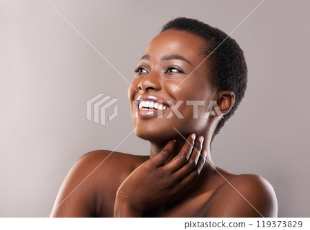 African beauty. Portrait of happy beautiful black woman touching her soft skin and looking upwards at copy space on grey background 119373829