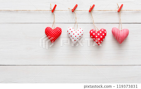 Valentine background with sewed pillow hearts row border on red clothespins at rustic white wood planks. Happy lovers day card mockup, copy space Valentine background with sewed pillow hearts row border on red clothespins at rustic white wood planks. Happy lovers day card mockup, copy space 119373831