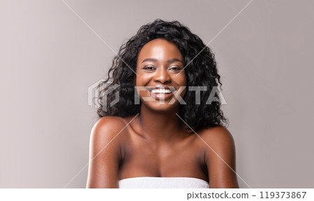 Beauty and body care. Portrait of young beautiful african woman in bath towel, grey background 119373867