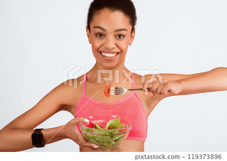 Fitness Nutrition. Fit Black Girl Eating Vegetable Salad From Bowl Standing In Studio Over Pink Background Fitness Nutrition. Fit Black Girl Eating Vegetable Salad From Bowl Standing In Studio Over Pink Background 119373896