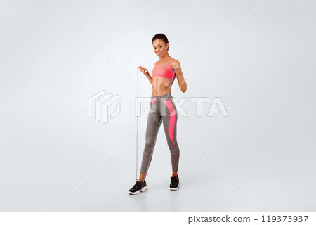 Slim Afro Woman Exercising With Jump Rope Smiling At Camera Standing Over Pink Studio Background. Full Length, Copy Space Slim Afro Woman Exercising With Jump Rope Smiling At Camera Standing Over Pink Studio Background. Full Length, Copy Space 119373937
