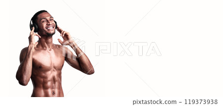 Fitness Playlist. Shirtless African Sporty Guy In Headphones Listening To Music Enjoying Favorite Song Over White Studio Background. Empty Space 119373938