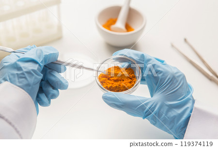 Medicine research of curcuma properties with the help of laboratory equipment, man in gloves testing turmeric powder Medicine research of curcuma properties with the help of laboratory equipment, man in gloves testing turmeric powder 119374119