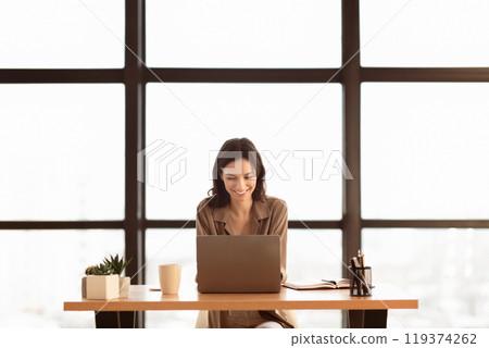 Freelance. Front view of happy woman using laptop, working at home, writing a blog, copyspace Freelance. Front view of happy woman using laptop, working at home, writing a blog, copyspace 119374262
