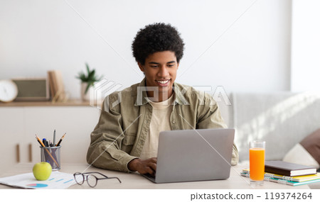E-learning concept. African American teenager studying online on laptop computer at home. Black youth using PC to make home assignment, talk to his college teacher or fellow students on webcam 119374264