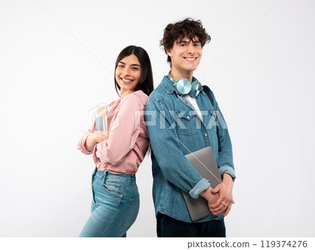 Modern Students. Happy Young Couple With Laptop And Workbooks Posing Standing Back To Back On White Studio Background, Smiling To Camera. Technology And Education, Great E-Learning Offer Concept 119374276