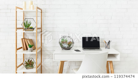 Home working place with laptop, and home plants on rack at white brick wall background. Minimalistic modern interior concept, copy space 119374474