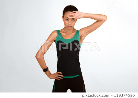 Fitness Concept. Sporty Afro Girl Wiping Sweat From Face After Workout Training Standing Over Yellow Studio Background 119374580