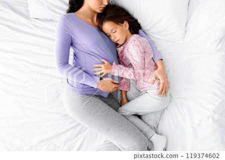 Peaceful image of expecting young woman having nap with little daughter at home, top view 119374602