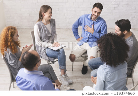 Cheerful man appreciates support of people at rehab group meeting, empty space Cheerful man appreciates support of people at rehab group meeting, empty space 119374660