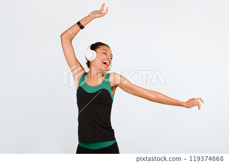 Black Sporty Girl In Wireless Earphones Listening To Music Dancing And Singing Over Yellow Studio Background. 119374668
