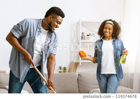 Happy Black Couple Enjoying Cleaning House Together, Man Washing Floor At Home While Woman Using Sponge And Sprayer, Free Space Happy Black Couple Enjoying Cleaning House Together, Man Washing Floor At Home While Woman Using Sponge And Sprayer, Free Space 119374678