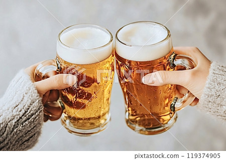 Two people clinking glasses of beer together celebrating 119374905