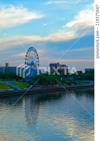 The Ferris wheel at Arakawa Amusement Park and the scenery reflected on the Sumida River. Evening view. Sunset. The Ferris wheel at Arakawa Amusement Park and the scenery reflected on the Sumida River. Evening view. Sunset. 119375687