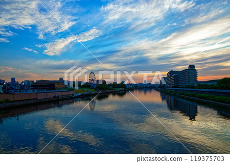 The Ferris wheel at Arakawa Amusement Park and the scenery reflected on the Sumida River. Evening view. Sunset. The Ferris wheel at Arakawa Amusement Park and the scenery reflected on the Sumida River. Evening view. Sunset. 119375703