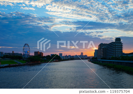 The Ferris wheel at Arakawa Amusement Park and the scenery reflected on the Sumida River. Evening view. Sunset. The Ferris wheel at Arakawa Amusement Park and the scenery reflected on the Sumida River. Evening view. Sunset. 119375704