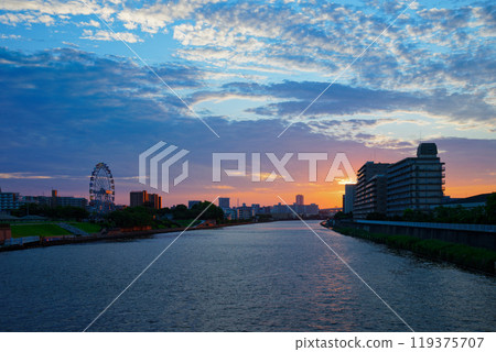The Ferris wheel at Arakawa Amusement Park and the scenery reflected on the Sumida River. Evening view. Sunset. The Ferris wheel at Arakawa Amusement Park and the scenery reflected on the Sumida River. Evening view. Sunset. 119375707