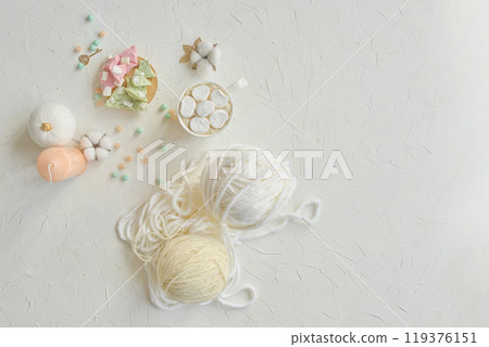 A delicate arrangement of yarn balls, pastel colored beads, and crafting materials on a light textured surface. A delicate arrangement of yarn balls, pastel colored beads, and crafting materials on a light textured surface. 119376151