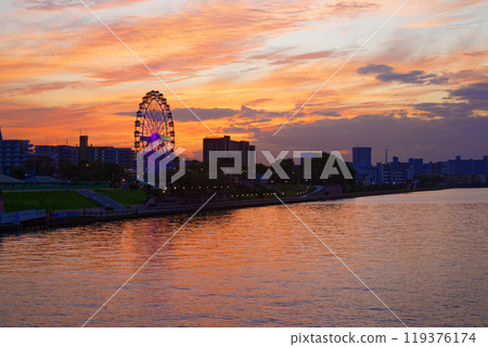 Arakawa Amusement Park's Ferris wheel and the scenery reflected in the Sumida River. Evening scenery, sunset, night view, light-up 119376174