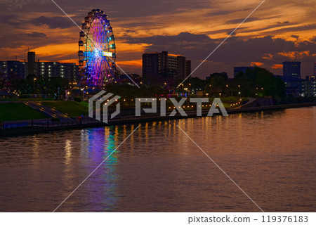Arakawa Amusement Park's Ferris wheel and the scenery reflected in the Sumida River. Evening scenery, sunset, night view, light-up 119376183