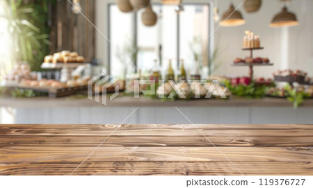 A wooden table top sits in front of a blurred background of a lavish buffet with desserts, flowers, and beverages. 119376727