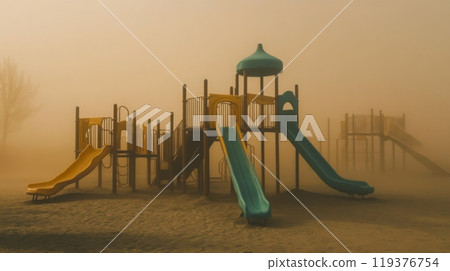 A vibrant playground is enveloped in thick fog, creating an eerie yet beautiful atmosphere. The colorful slides and climbing equipment appear somewhat haunting in the misty setting. A vibrant playground is enveloped in thick fog, creating an eerie yet beautiful atmosphere. The colorful slides and climbing equipment appear somewhat haunting in the misty setting. 119376754