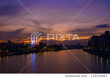 The Ferris wheel at Arakawa Amusement Park and the scenery reflected on the Sumida River. Evening view. Sunset. The Ferris wheel at Arakawa Amusement Park and the scenery reflected on the Sumida River. Evening view. Sunset. 119376967