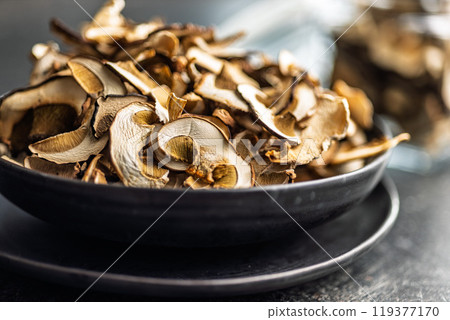 Dried porcini mushrooms. Sliced boletus on plate on black table. 119377170