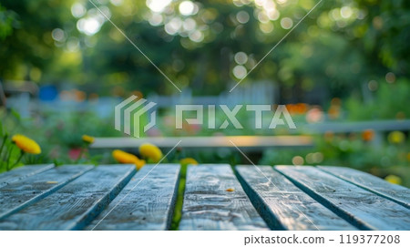 A close-up view of a weathered wooden picnic table, positioned in a lush green garden setting. 119377208